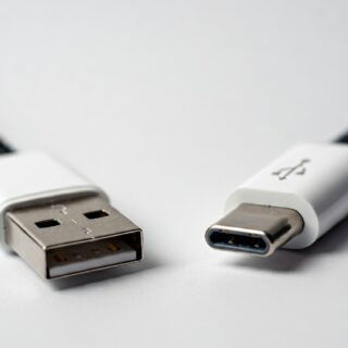 Minimalistische Illustration der USB-Technologieentwicklung mit vereinfachten Darstellungen von USB-Steckern und Kabeln der Generationen von USB 1.0 bis USB4, chronologisch angeordnet.
