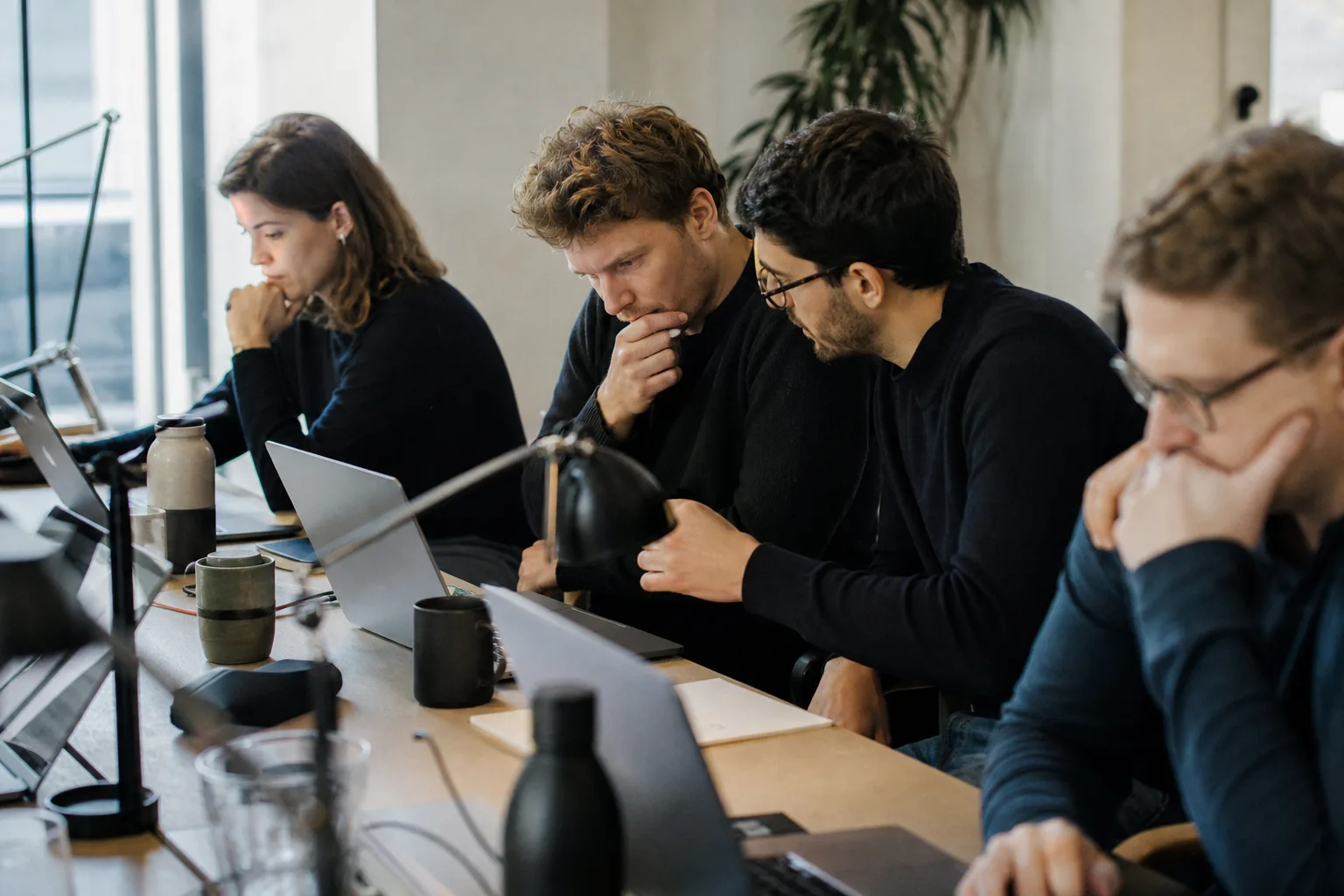 Team in einem europäischen Büro arbeitet mit KI-gestützten Workflows an Laptops