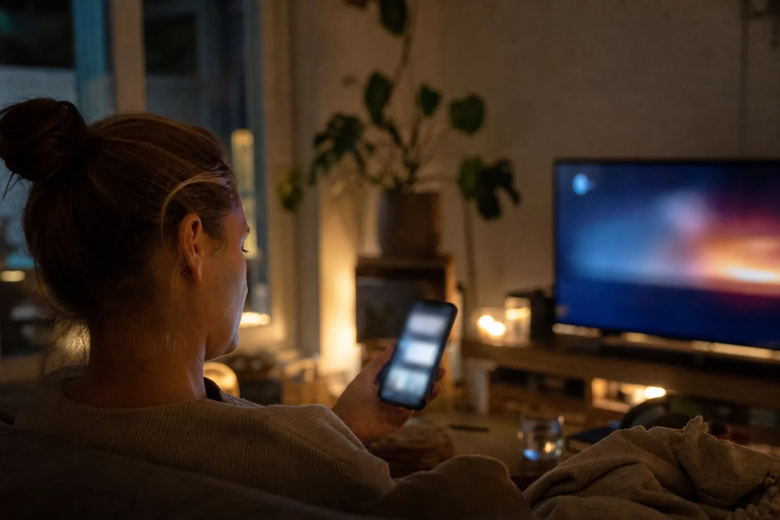 Person überlegt auf dem Sofa vor einem Smartphone, welchen Film oder welche Serie sie sehen möchte.