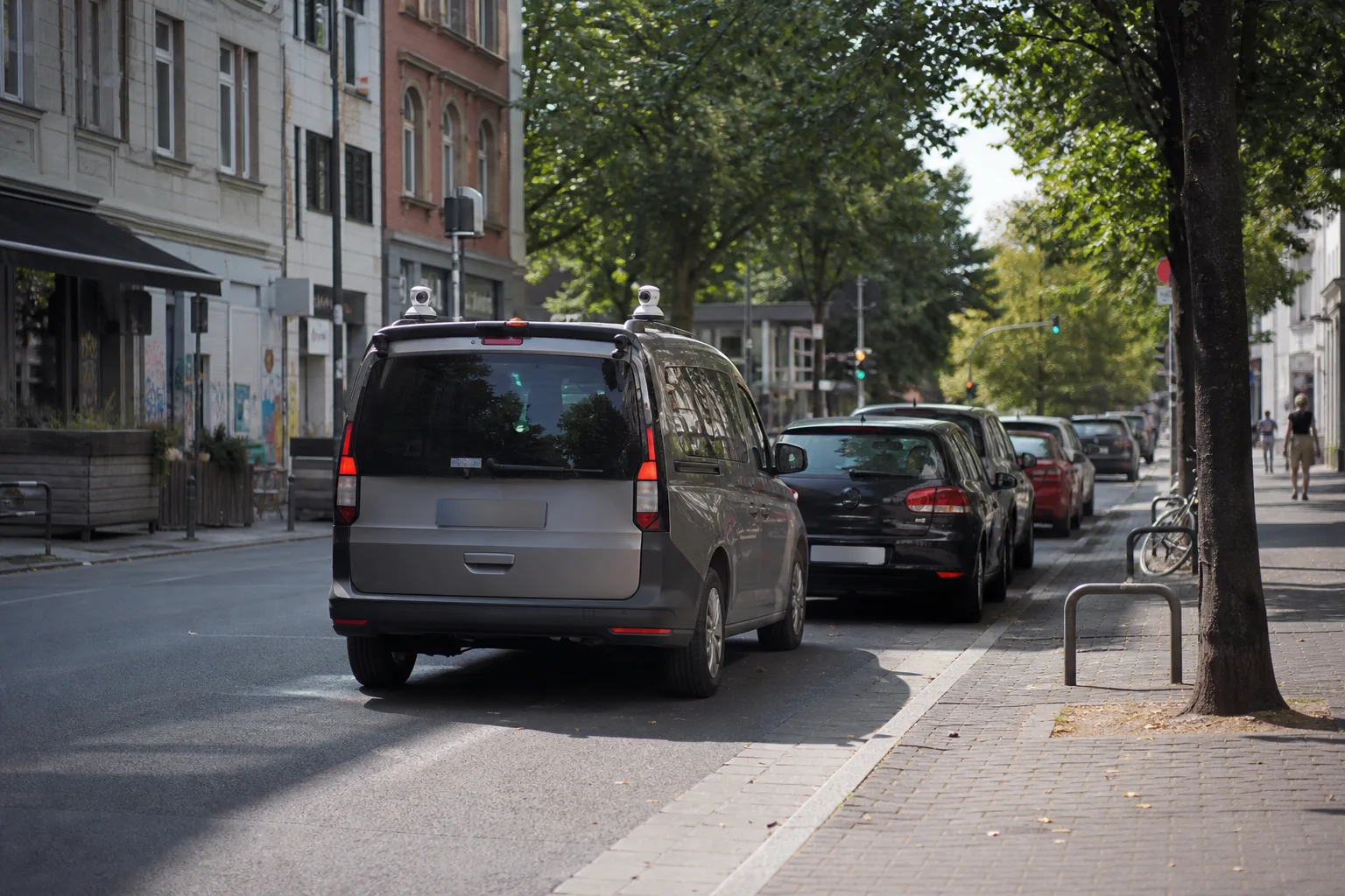 Kamerawagen fährt an geparkten Autos vorbei und symbolisiert digitale Parkraumkontrolle.