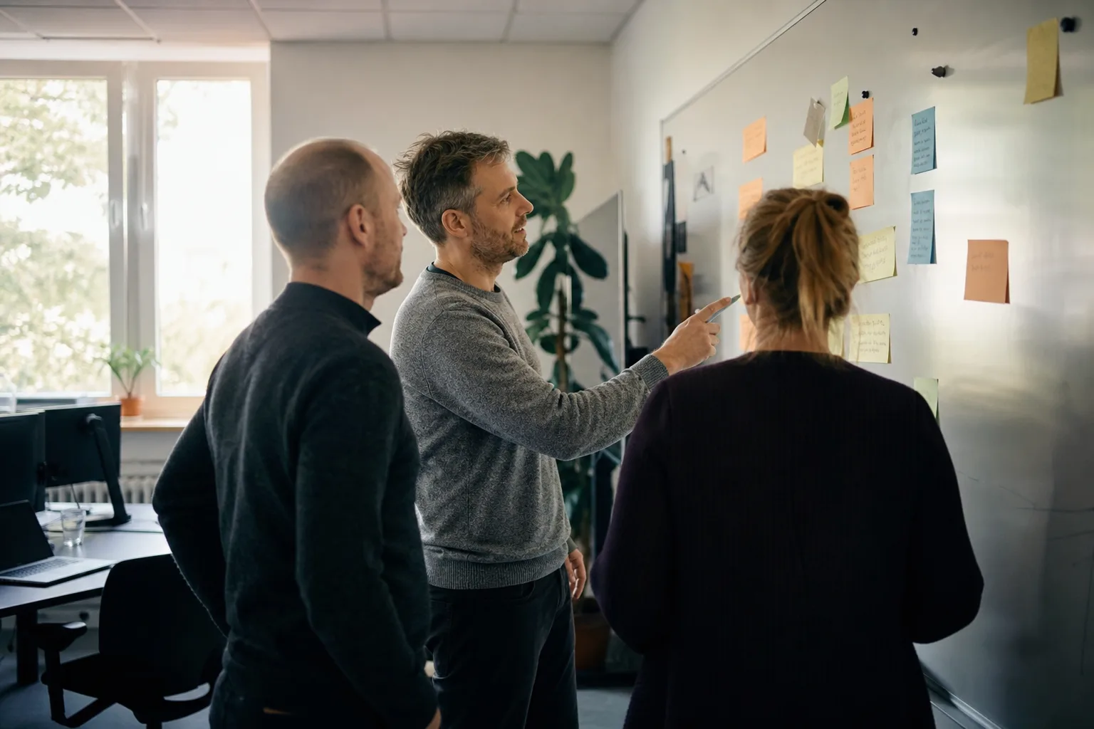 Team in einem mittelständischen Büro sortiert KI-Prozesse und Verantwortlichkeiten an einem Whiteboard