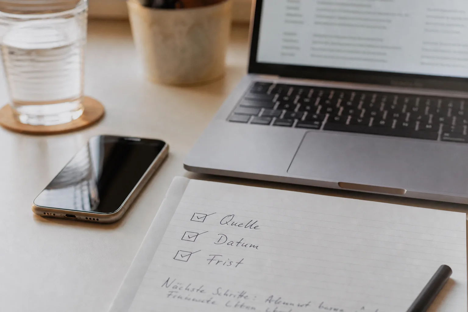Checkliste zur Quellenprüfung neben Smartphone und Laptop.