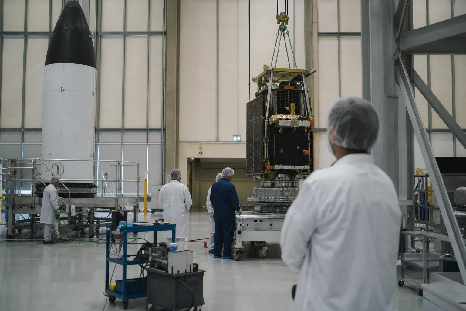 Technikerinnen und Techniker bereiten einen anonymen Träger und Satelliten in einer europäischen Startanlagen-Halle vor