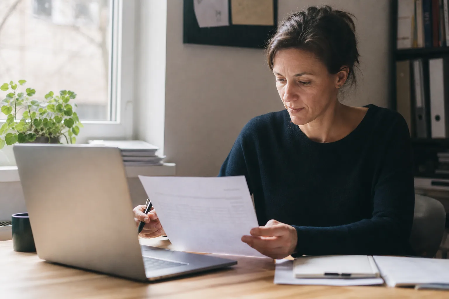 Freelancerin prüft eine Rechnung für einen französischen Geschäftskunden an einem Schreibtisch