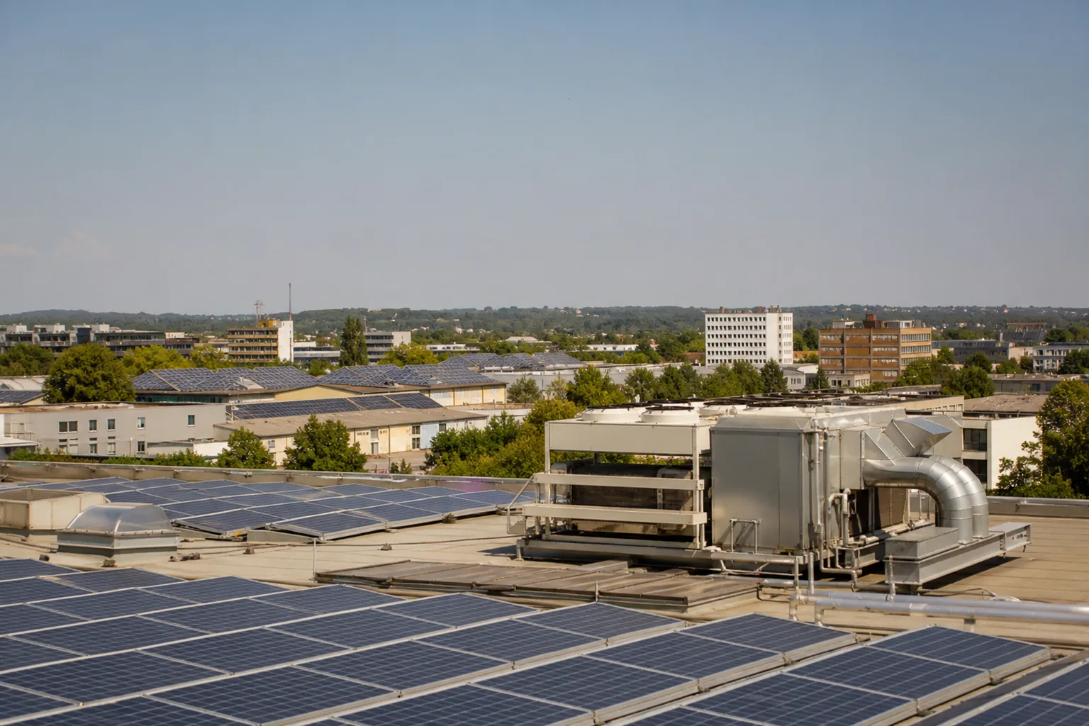 Photovoltaikflächen auf Gewerbedächern neben einer unaufdringlichen Kühlanlage an einem heißen, klaren Nachmittag