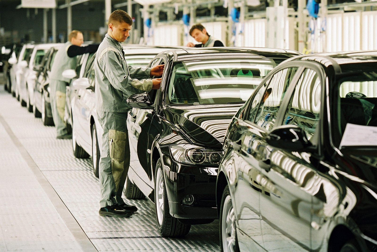 Qualitätskontrolle an der Automontagelinie: Mitarbeiter prüft ein Fahrzeug am Band – Symbolbild für Inferenz nah an den Produktionsdaten